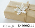 Christmas and New Year background. Gift box wrapped in kraft paper with jute cord. Decorated with a crocheted snowflake 84999211