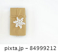 Christmas and New Years flatlay background. Gift box wrapped in kraft paper with jute cord. Decorated with a crocheted snowflake. Place for your text 84999212