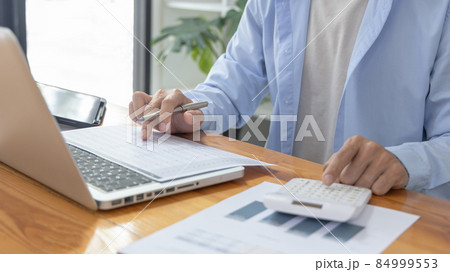 Businessman presses a calculator to calculate earnings and analyze company earnings in his private office, Information in finance and accounting, Company performance and revenue. 84999553