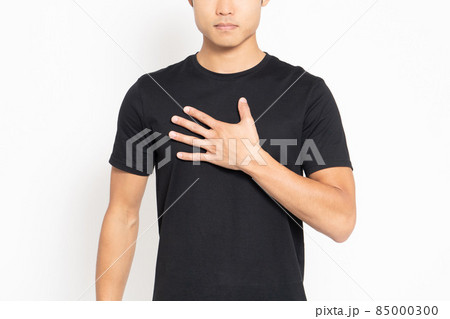 白い背景の前に立って胸に手を当てる黒いTシャツを着ている男性 白い背景の前に立って胸に手を当てる黒いTシャツを着ている男性 85000300