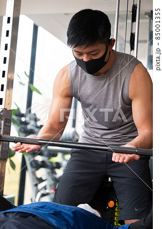 筋トレを教えるトレーナーとプライベートレッスンをバーベルの受ける人　縦 85001355