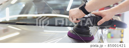 Man with an orbital polisher in car workshop polishing car closeup Man with an orbital polisher in car workshop polishing car closeup 85001421