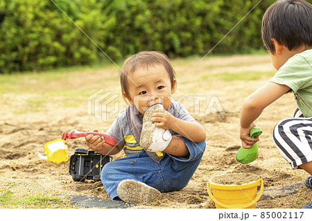 お兄ちゃんと砂場で遊びながら 自分の履いている靴に噛みつく男の子 汚れた靴を口に入れるの写真素材 お兄ちゃんと砂場で遊びながら 自分の履いている靴に噛みつく男の子 汚れた靴を口に入れるの写真素材