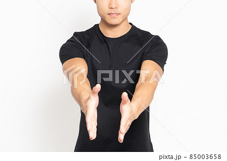 白い背景の前に立って手を差し出す黒いTシャツを着ている男性 白い背景の前に立って手を差し出す黒いTシャツを着ている男性 85003658