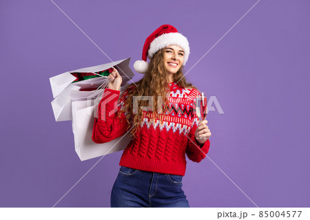 Happy girl holds shopping bags and champagne on purple background. Christmas sales. Black Friday 85004577