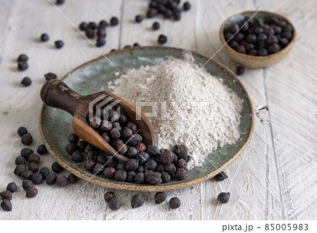 Plate of black chickpea flour and beans with a wooden spoon closeup Plate of black chickpea flour and beans with a wooden spoon closeup 85005983