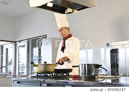 飲食店の厨房でコック服を着たシニア男性が料理を作る 飲食店の厨房でコック服を着たシニア男性が料理を作る 85006287