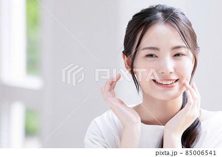 お肌の調子を気にして微笑む美しい若いアジア人(日本人)女性 クローズアップ コピースペースあり お肌の調子を気にして微笑む美しい若いアジア人(日本人)女性 クローズアップ コピースペースあり 85006541