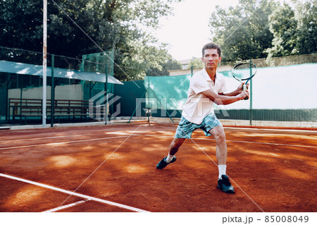 Fit man plays tennis on tennis field 85008049
