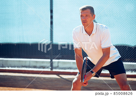 Tennis player standing in ready position on tennis court 85008626