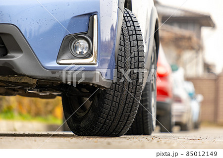 Closeup of parked car on a city street side with new winter rubber tires. Closeup of parked car on a city street side with new winter rubber tires. 85012149