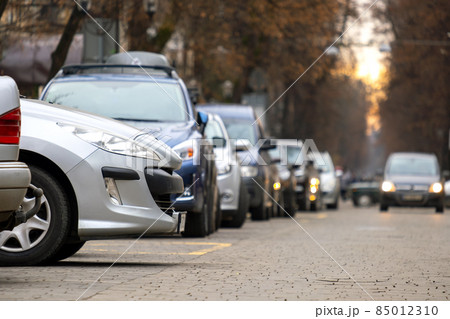 Cars parked in a row on a city street side. 85012310
