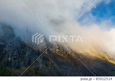 Mystical mountains. Atmospheric scenery on top of mountain ridge above thick low clouds. Beautiful alpine landscape with mountain range over dense clouds. 85012514