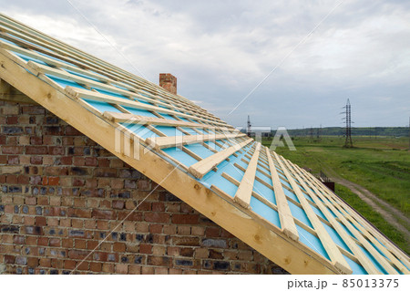 Aerial view of a brick house with wooden roof frame under construction. Aerial view of a brick house with wooden roof frame under construction. 85013375