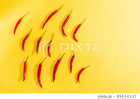 Red chili peppers on a yellow background. Topview creative composition with copy space Red chili peppers on a yellow background. Topview creative composition with copy space 85014137