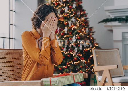 Curious woman covering eyes with hands and guessing what inside of Christmas gift box 85014210