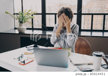 Curious woman office employee covering eyes with hands while getting x-mas present at work 85014451