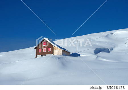 Winter landscape in the Swiss mountains: A beautiful hut on a snow covered mountains under the deeply blue sky 85018128