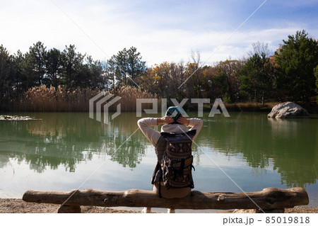 young woman hiker sits on a wooden bench by the lake in the mountains 85019818