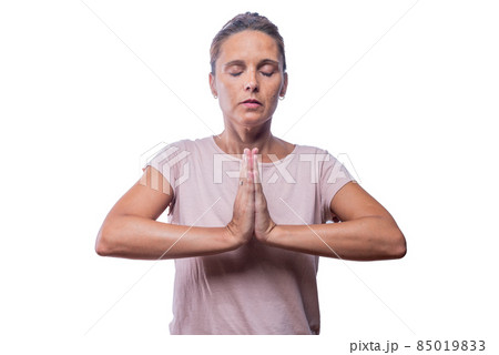 An adult woman standing meditating in prayer pose An adult woman standing meditating in prayer pose 85019833