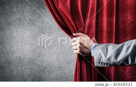 Concrete wall behind drapery curtain and hand opening it Concrete wall behind drapery curtain and hand opening it 85020532