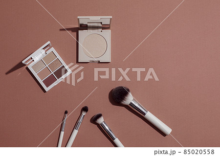 Pastel Eye shadow palette, highlighting powder and makeup brushes on pink background. 85020558