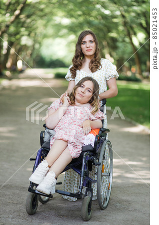 Woman in wheelchair with her female friend at park 85021453