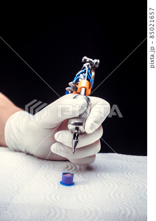 Hand of a tattoo artist with a tattoo gun. Hand of a tattoo artist with a tattoo gun. 85021657