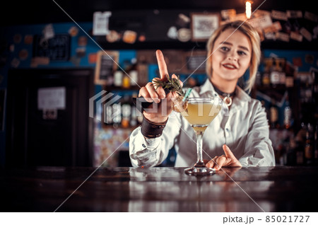 Professional girl bartending demonstrates his professional skills while standing near the bar counter in bar 85021727