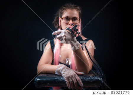 Master tattooist with a tattoo machine in tattoo parlor 85021776