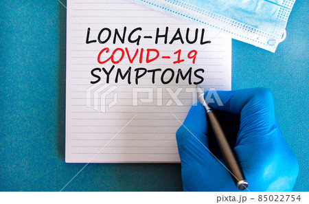 COVID-19 long-haul covid symptoms symbol. White card with words Long-haul covid-19 symptoms. Doctor hand, pen, blue background, copy space. Medical, COVID-19 long-haul covid symptoms concept. 85022754