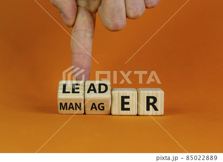 Manager versus leader symbol. Businessman flips wooden cubes and changes the word 'manager' to 'leader'. Beautiful orange background, copy space. Business and manager versus leader concept. 85022889