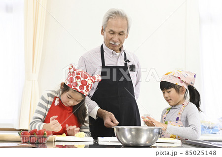 社会見学の体験教室で、ケーキの作り方を学ぶ小学生の女の子とシニア男性 85025148
