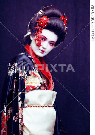 young pretty real geisha in kimono with sakura and decoration on black background 85025382