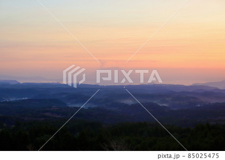 夕暮れの空に浮かぶ赤く染まった桜島と鹿児島空港に向かう飛行機(引き構図) 85025475