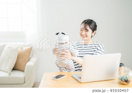 赤ちゃんを抱きながらパソコンを使う女性 85030407