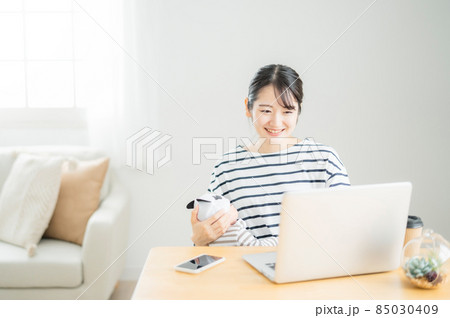 赤ちゃんを抱きながらパソコンを使う女性 85030409