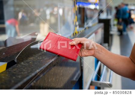Faceless woman giving her passport at the airport check-in counter. 85030828