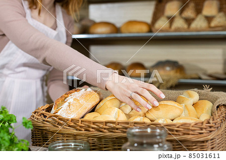 As fresh bread is delivered by a handsome baker, the attractive saleswoman offers one bun. Family bakery shop with multi-generation traditions. 85031611