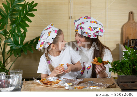 Satisfying yourself with heartfelt words in your ear while eating homemade pizza. Mom and daughter moments together in the home kitchen. 85032086