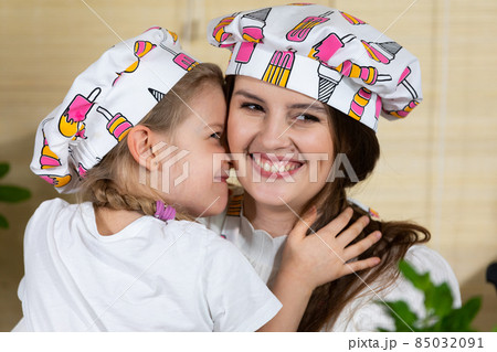 While eating home-made pizza, a five-year-old daughter hugs her mother warmly, thus reciprocating her mother's love for her child. While eating home-made pizza, a five-year-old daughter hugs her mother warmly, thus reciprocating her mother's love for her child. 85032091