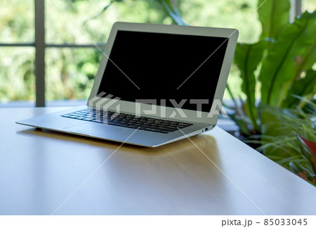 Black screen laptop computer on wooden table with greenery bokeh background. Black screen laptop computer on wooden table with greenery bokeh background. 85033045