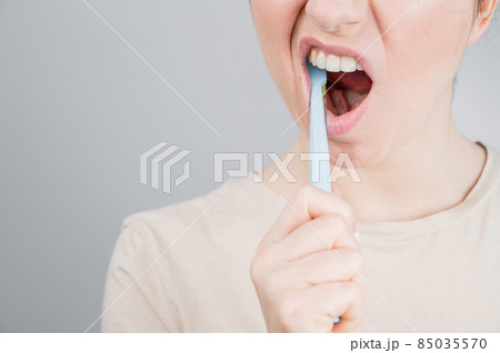 Close-up portrait of caucasian woman brushing her teeth. The girl performs the morning oral hygiene procedure Close-up portrait of caucasian woman brushing her teeth. The girl performs the morning oral hygiene procedure 85035570