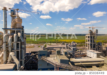 Aerial view of cement factory with high concrete structure and tower crane at industrial production area. Manufacture and global industry concept. Aerial view of cement factory with high concrete structure and tower crane at industrial production area. Manufacture and global industry concept. 85036449