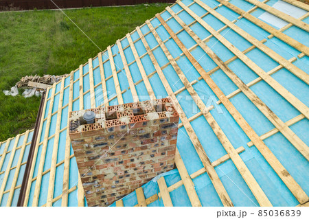 Aerial view of a wooden roof frame of brick house under construction. Aerial view of a wooden roof frame of brick house under construction. 85036839