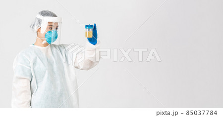 Covid-19, coronavirus disease, healthcare workers concept. Side view of serious-looking tech lab employee, researcher in personal protective equipment examine urine analyzes, white background Covid-19, coronavirus disease, healthcare workers concept. Side view of serious-looking tech lab employee, researcher in personal protective equipment examine urine analyzes, white background 85037784