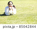 芝生で寛ぐ若い笑顔の女性 85042844