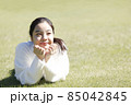 芝生で寛ぐ若い笑顔の女性 85042845