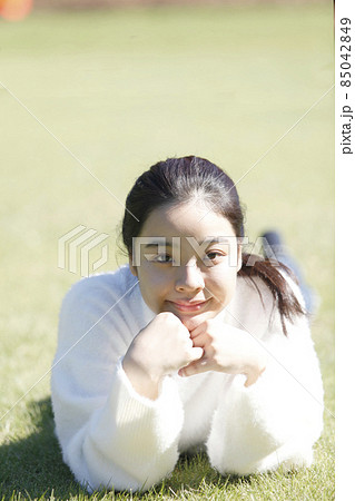 芝生で寛ぐ若い笑顔の女性正面 芝生で寛ぐ若い笑顔の女性正面 85042849