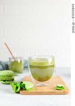 Japanese matcha green tea in thermal glasses and macaroon cake on a wooden stand. Close-up, on a gray background, vertical Japanese matcha green tea in thermal glasses and macaroon cake on a wooden stand. Close-up, on a gray background, vertical 85050845